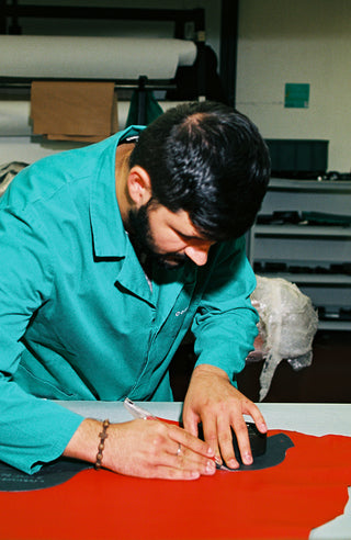 Artisan cutting leather in factory